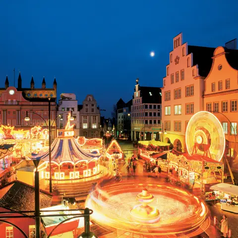 Julemarked og karusseller i smuk aftenbelysning i Rostock i Tyskland.