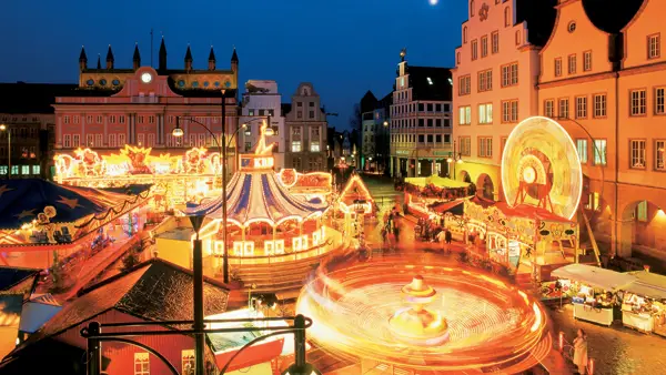 Julemarked og karusseller i smuk aftenbelysning i Rostock i Tyskland.