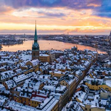 Luftfoto i aftensskumringen over Stockholm ved snehvide tage.